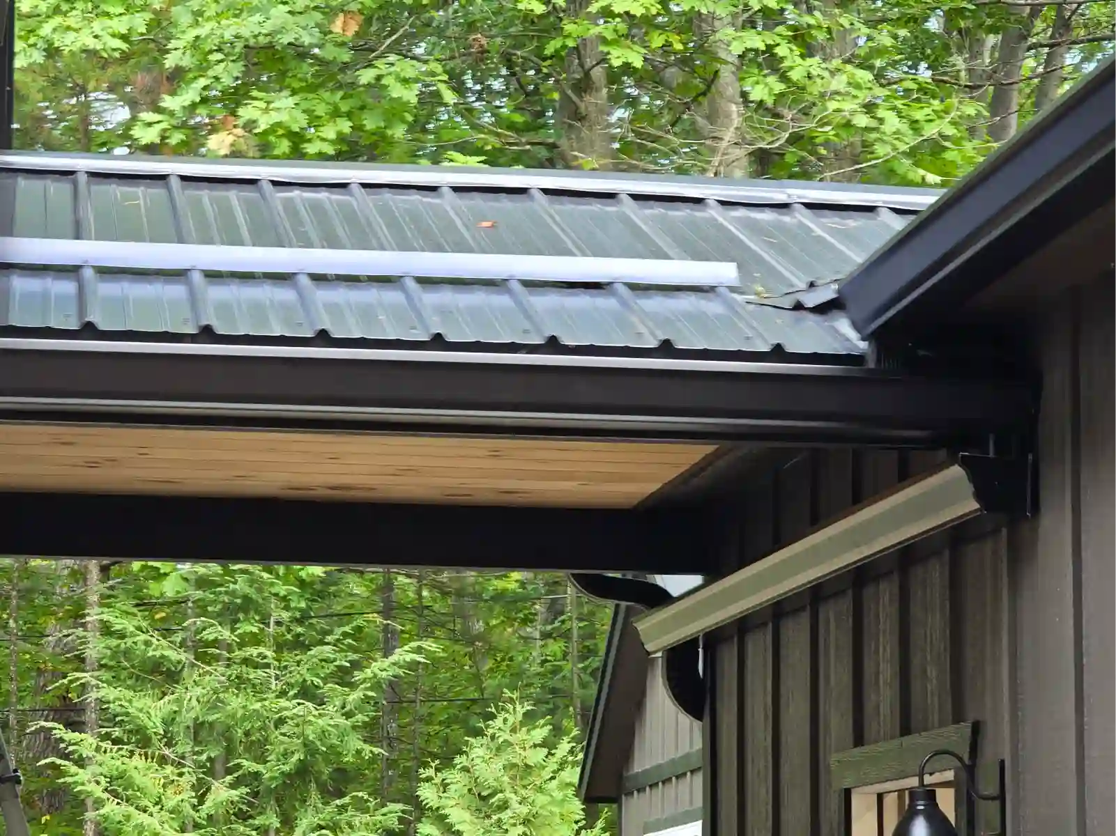 Metal roof edge and new gutter over a wood-sided home