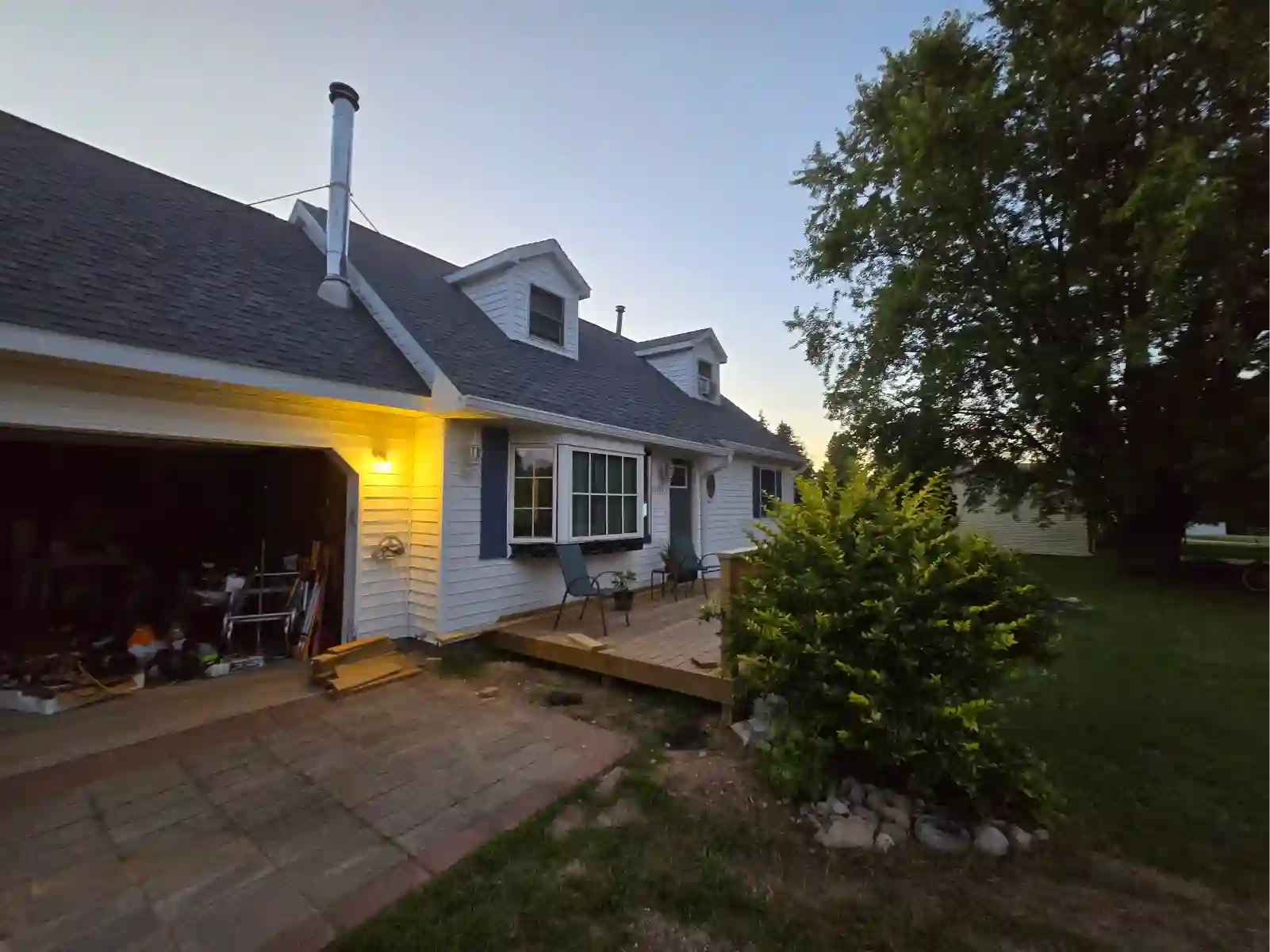 Shingle roof and dormers over a white home at dusk