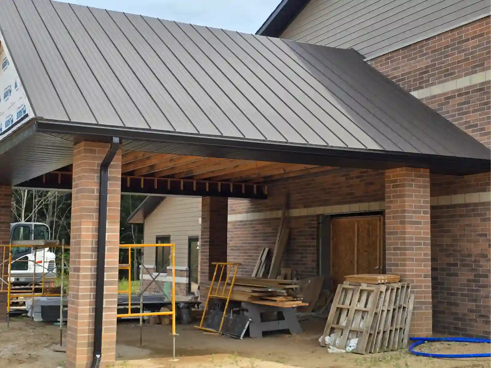Brown metal roof over a brick carport under construction