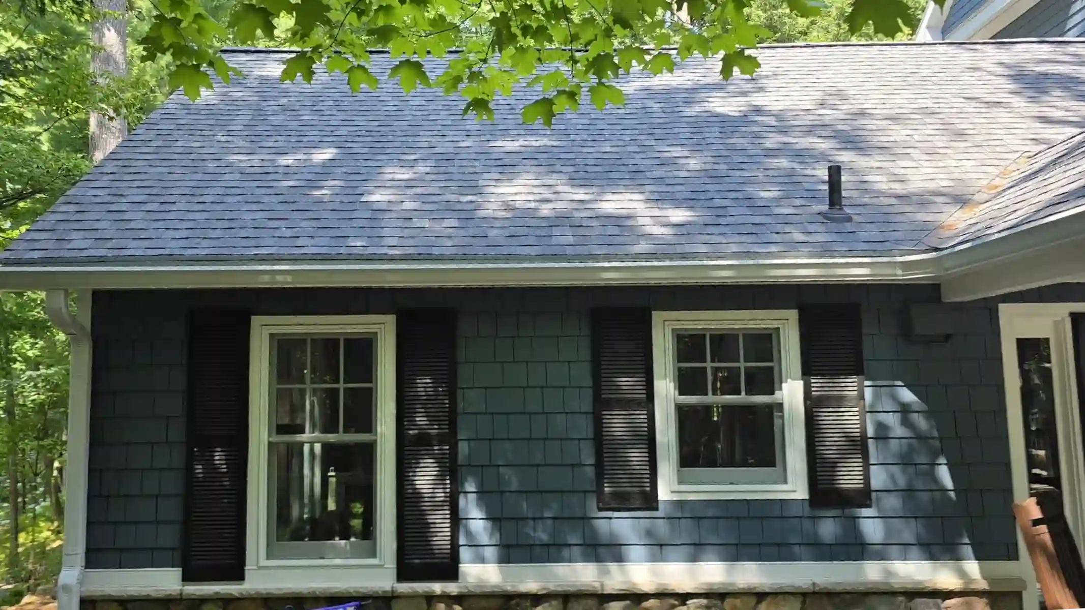 Aging asphalt shingle roof over a blue-sided home