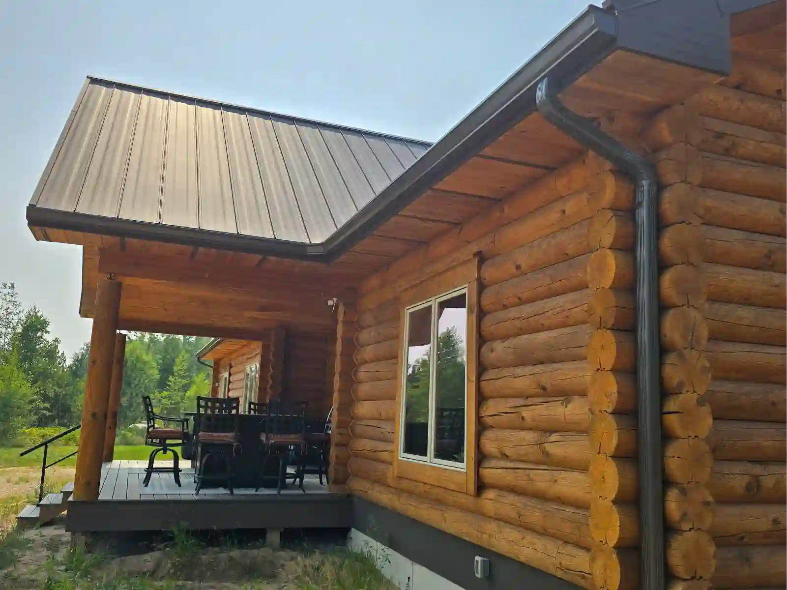 Log home with dark seamless gutters and metal roof